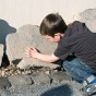 Kleiner Junge erfühlt eingemeißelte Schrift auf einer Steintafel.