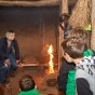 In einem Holz-Lehm-Haus wurde Feuer gemacht. Schülerinnen und Schüler schauen, wie die erste Flamme auflodert.