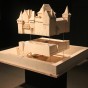 Ausstellungsraum. In der Mitte steht ein weiß gestrichenes Modell von Haus Pesch. Der Graben, das Untergeschoss und das aufgehende Mauerwerk schweben voneinander getrennt mit Lücken übereinander.