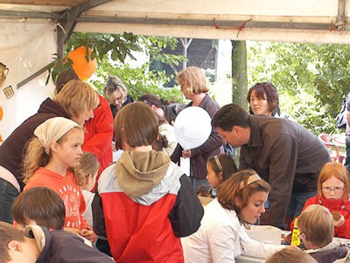 Eine Gruppe von Kindern stehend und an Tischen sitzend im Kinderzelt.