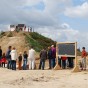 Besuchergruppen auf der Ausgrabungsfläche. Im Hintergrund eine künstliche Anhöhe mit Besuchern und Schautafeln.