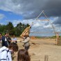 Foto: Blick über die Grabungsfläche mit Besuchern. Im Hintergrund befindet sich die Kippe und zwei Braunkohlekraftwerke. Links im Bild steht ein Bagger.