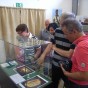 Einige Besucher schauen in eine Vitrine. Darin liegen ein Goldring und ein Bleisiegel und Fotos der Fundstücke.