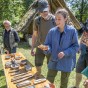 Auf einem Tisch liegen Utensilien für den Bronzeguss. Eine Besucherin hat eine Gussform in der Hand.