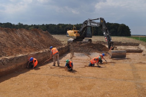 Das Foto zeigt Arbeiter beim Putzen eines Grabungsplanums.