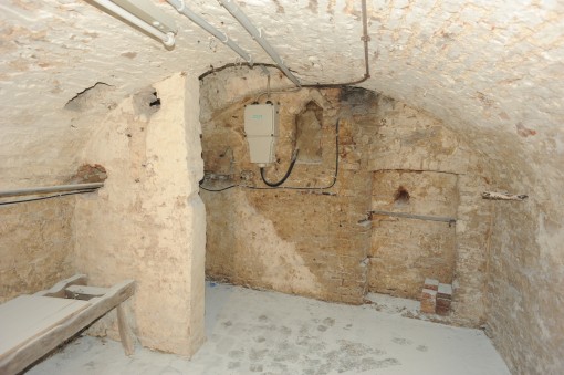 Keller mit Korbbogengewölbe des 18. Jahrhunderts. In der Backsteinwand eine große Wandnische für ein Regal und eine kleine Nische für Kerzenlicht. Im Gewölbe ein Kellerzugang sowie ein kleines Kellerfenster. 