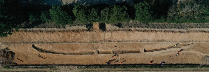 Drohnenfoto: Das Foto zeigt eine Grabungssituation von 2021 aus der Luft. Der Graben ist ausgenommen und gut sichtbar. Zwei Stege sind vorhanden um zusätzliche Profile dokumentieren zu können.