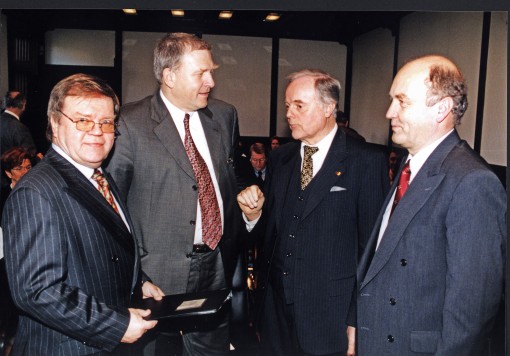 Vier im Anzug gekleidete Männer führen nach der Vorlesung fachliche Gespräche.